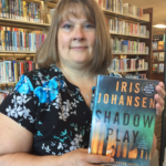 Staff member Dawn holding a copy of the book Shadow Play