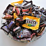 Glass bowl holding various packaged small candy.