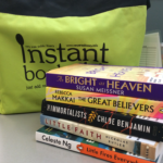 Photo of books stacked in front of green canvas bag
