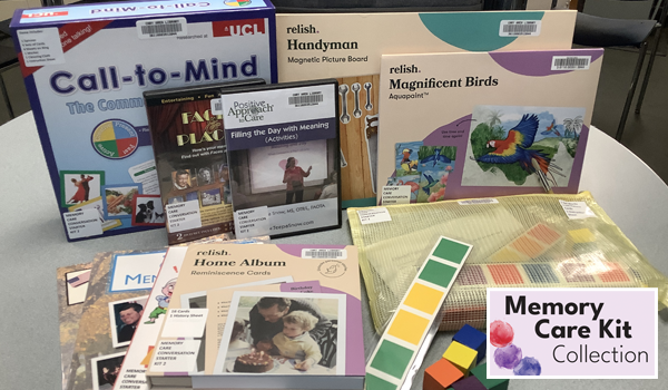 Photo of items laid out on a table from one of the Memory Care Kits, including books, DVDs, and blocks in purple, green, yellow, and orange.