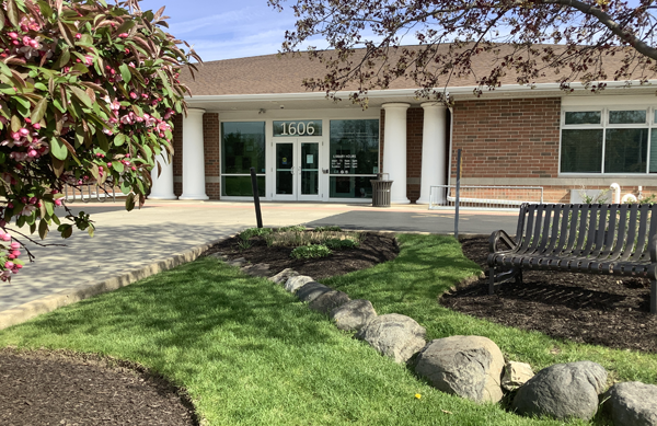 Front entrance of the Library, with a crabapple tree and bench in the foreground.