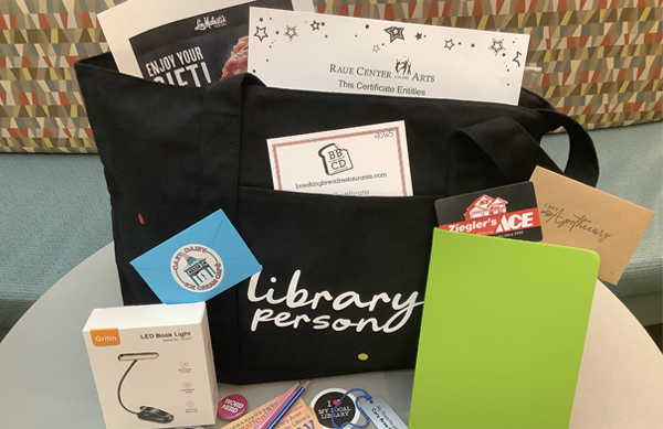 Prize contents: a black tote bag with "Library person" text in white, surrounded by gift cards, and bookish and library-branded items.