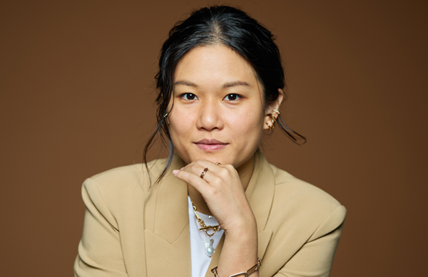 Headshot of Karen Hao. She has her hand on her chin and is wearing a tan blazer over a white shirt