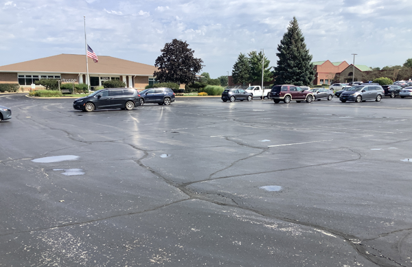 Library parking lot from the southwest corner. Several cars are parked and the Library building is in the background.